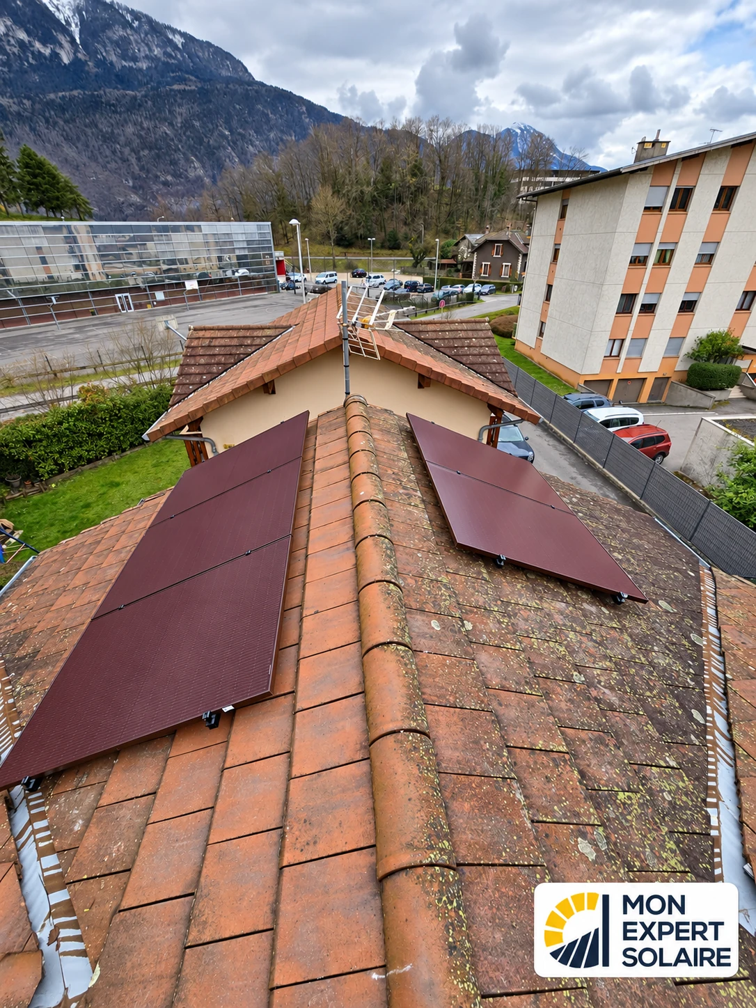 Détail de modules photovoltaïques rouge bordeaux installés sur une toiture en tuiles.